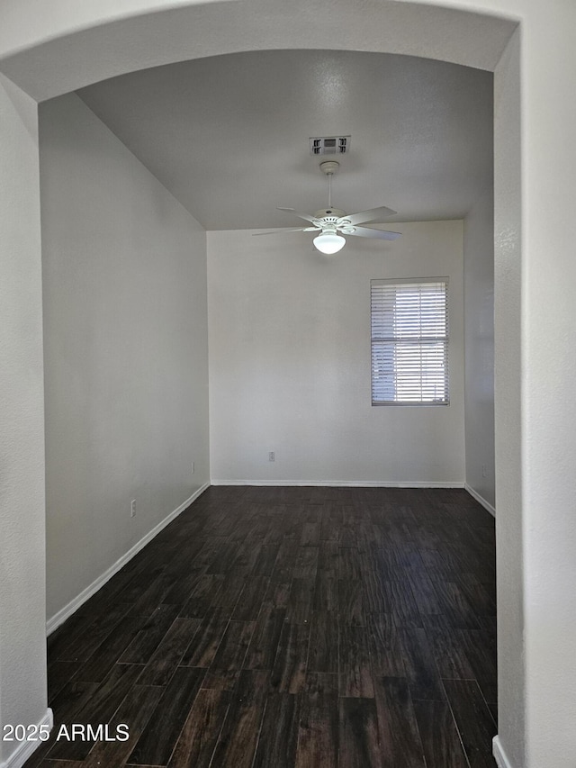 empty room featuring visible vents, baseboards, dark wood-type flooring, and a ceiling fan