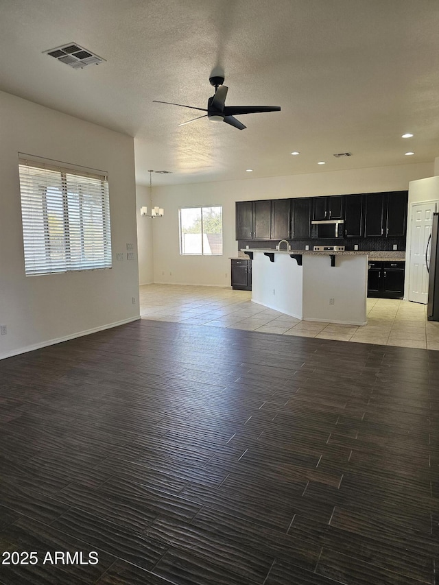 unfurnished living room featuring recessed lighting, visible vents, ceiling fan with notable chandelier, and light wood-type flooring