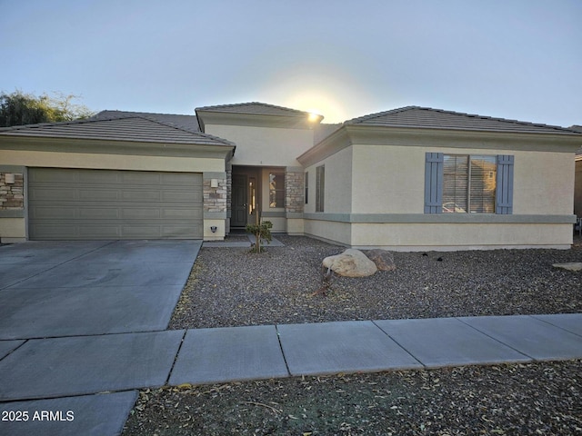 view of front of house with an attached garage, stone siding, driveway, and stucco siding