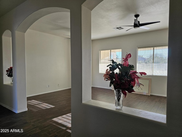 interior space with visible vents, a ceiling fan, a textured ceiling, wood finished floors, and arched walkways