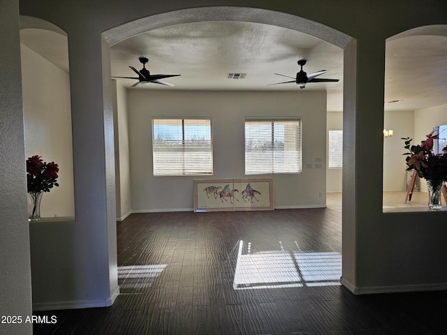 unfurnished living room with wood finished floors, visible vents, baseboards, ceiling fan, and a textured ceiling