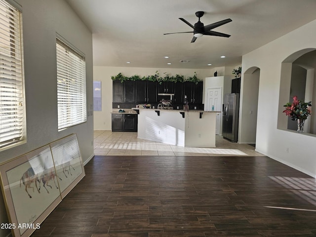 living area with recessed lighting, arched walkways, light wood finished floors, and ceiling fan