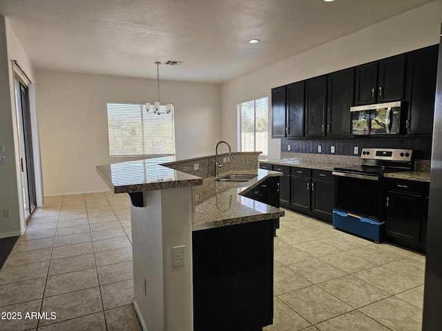 kitchen with a sink, stainless steel appliances, dark cabinets, and light tile patterned floors