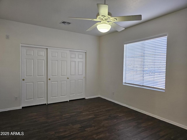 unfurnished bedroom featuring visible vents, dark wood-style floors, a closet, baseboards, and ceiling fan