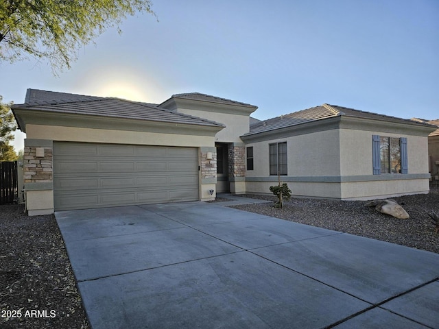 prairie-style home with a garage, stone siding, driveway, and stucco siding