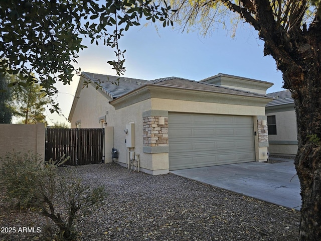 view of front of property with fence, stucco siding, concrete driveway, a garage, and stone siding