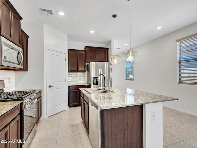 14160 W Georgia Dr, Surprise, AZ 85379 - kitchen featuring stainless steel appliances, a sink, light tile patterned flooring, decorative backsplash, and an island with sink