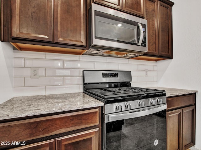14160 W Georgia Dr, Surprise, AZ 85379 - kitchen with appliances with stainless steel finishes, decorative backsplash, dark brown cabinets, and light stone counters