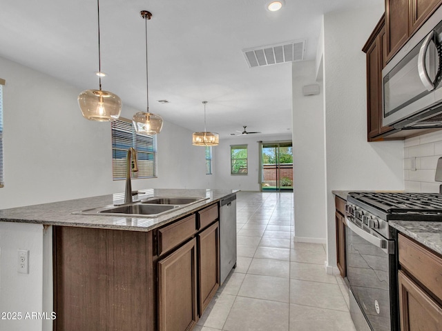 14160 W Georgia Dr, Surprise, AZ 85379 - kitchen featuring appliances with stainless steel finishes, a sink, light tile patterned flooring, an island with sink, and hanging light fixtures