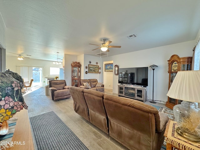 living room featuring a fireplace and ceiling fan with notable chandelier