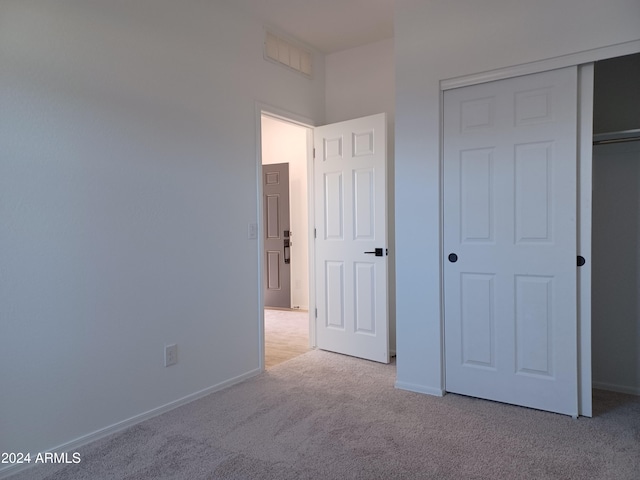 unfurnished bedroom featuring light colored carpet and a closet