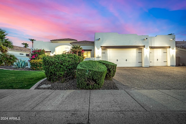 view of front of house featuring driveway, an attached garage, and stucco siding