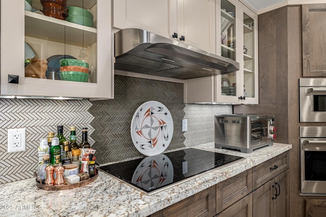 kitchen featuring a toaster, backsplash, glass insert cabinets, and range hood