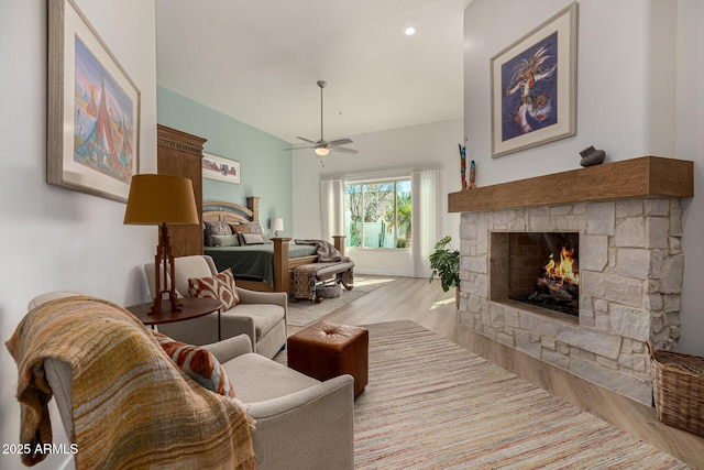 living area with a fireplace, a ceiling fan, and wood finished floors