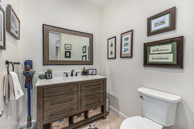 half bath with toilet, baseboards, and vanity