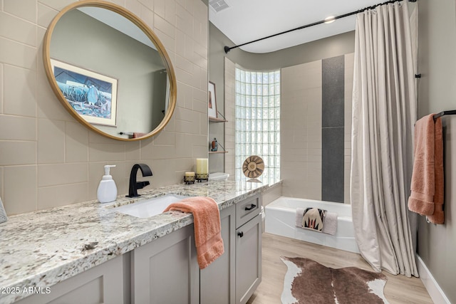 full bath featuring visible vents, shower / tub combo with curtain, wood finished floors, vanity, and backsplash