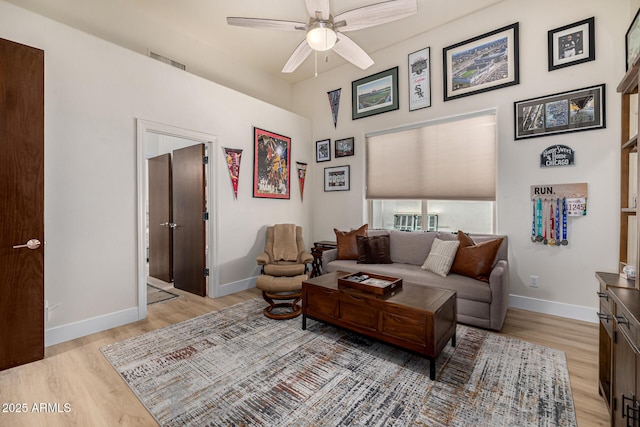 living area featuring visible vents, a ceiling fan, light wood-style flooring, and baseboards