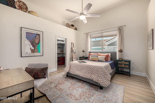 bedroom featuring light wood-style flooring, baseboards, a walk in closet, and a closet