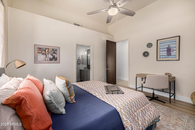 bedroom with ensuite bath, baseboards, visible vents, and wood finished floors