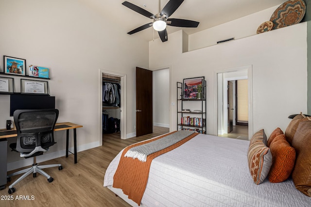 bedroom with baseboards, visible vents, wood finished floors, a spacious closet, and a closet