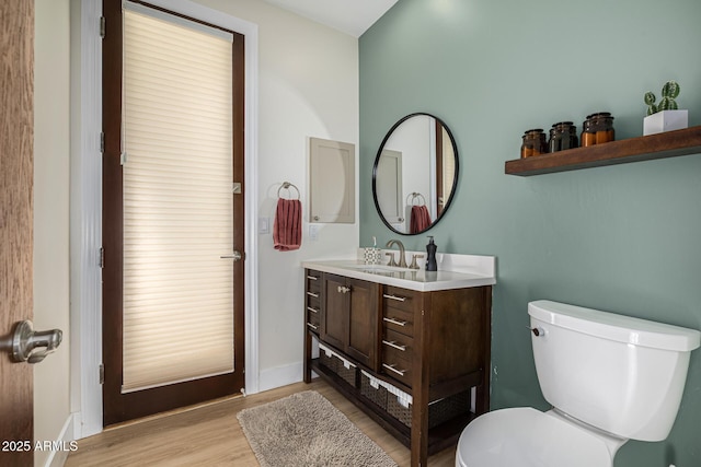 bathroom featuring vanity, wood finished floors, toilet, and baseboards