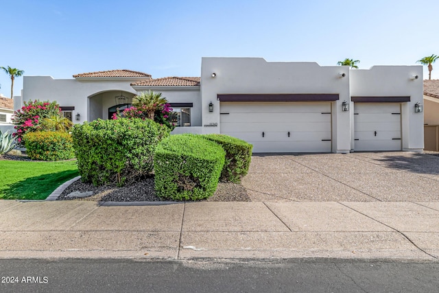 view of front of property with concrete driveway, a tiled roof, an attached garage, and stucco siding