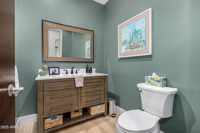 bathroom featuring baseboards, vanity, toilet, and wood finished floors