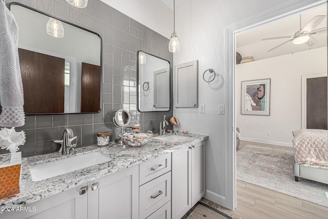 full bath with wood finished floors, double vanity, tasteful backsplash, and a sink