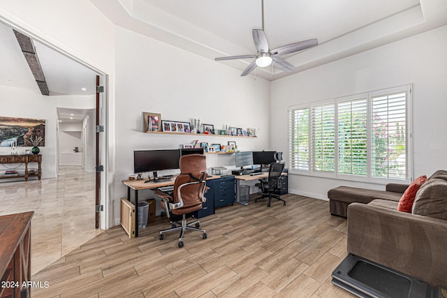 home office with wood tiled floor, baseboards, ceiling fan, and a raised ceiling