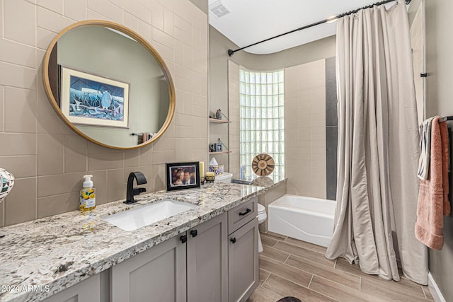 bathroom with wood finish floors, tile walls, vanity, visible vents, and decorative backsplash