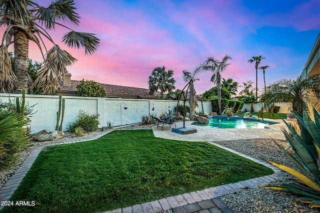 yard at dusk with a fenced in pool, a patio area, and a fenced backyard