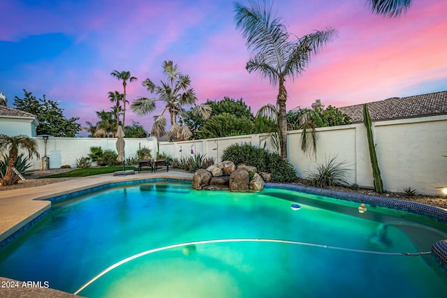 pool at dusk with a fenced in pool and a fenced backyard