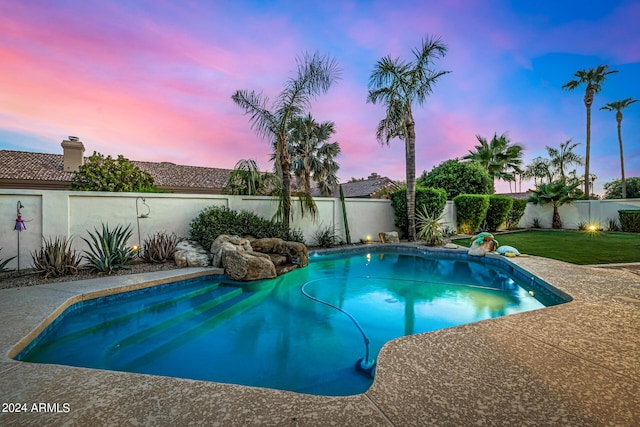 pool at dusk with a yard, a fenced backyard, and a fenced in pool