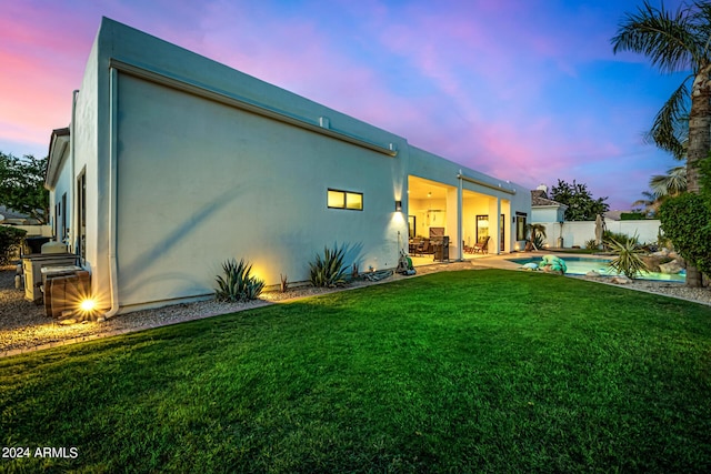 rear view of house with a fenced in pool, a patio, a lawn, fence, and stucco siding