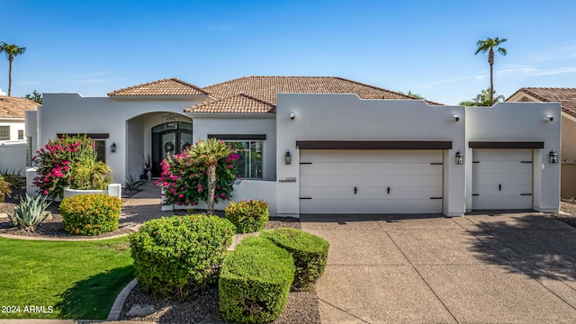 view of front of house featuring a garage, a tile roof, concrete driveway, and stucco siding