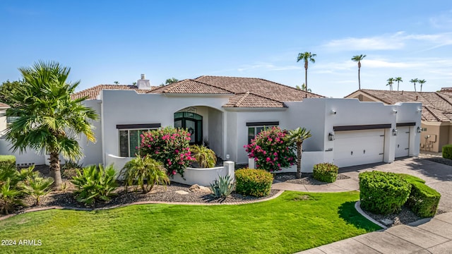 mediterranean / spanish home with driveway, a tiled roof, an attached garage, a front lawn, and stucco siding