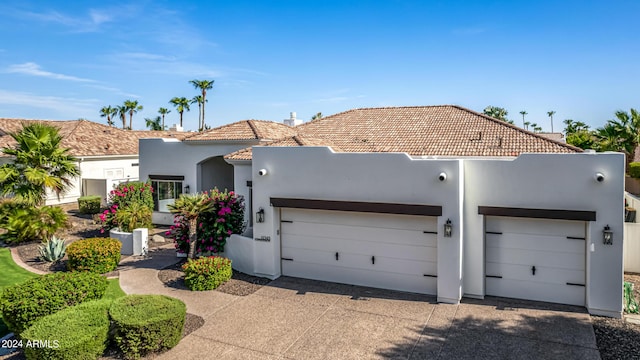 view of front of house featuring driveway, a tiled roof, a garage, and stucco siding