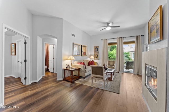 7887 N 16th St Unit 226, Phoenix, AZ 85020 - living room featuring arched walkways, a ceiling fan, a glass covered fireplace, wood finished floors, and baseboards