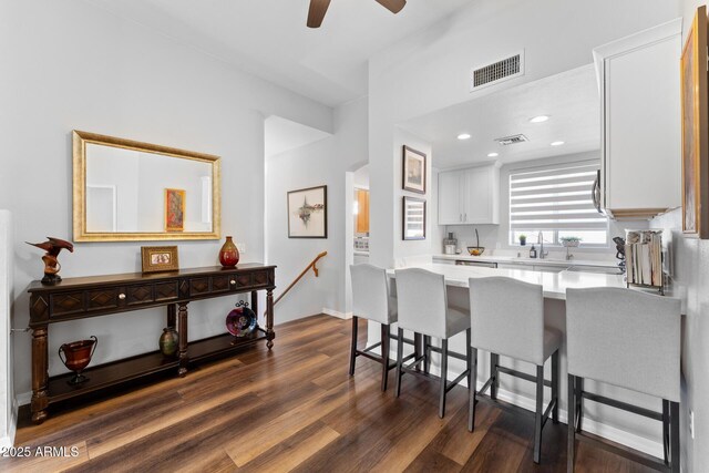 7887 N 16th St Unit 226, Phoenix, AZ 85020 - kitchen featuring light countertops, white cabinetry, a breakfast bar, a peninsula, and dark wood-type flooring