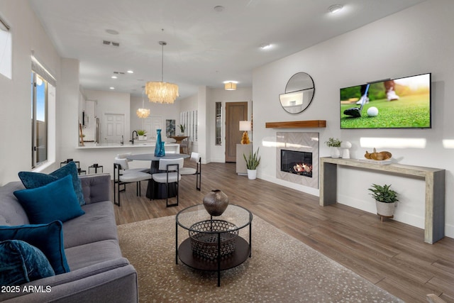 living room with a fireplace, hardwood / wood-style floors, sink, and a notable chandelier