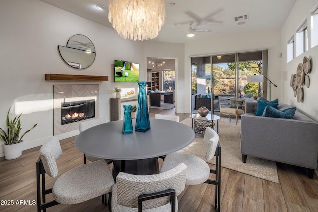 dining area featuring hardwood / wood-style flooring, a chandelier, and a tile fireplace