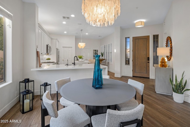 dining area featuring sink, hardwood / wood-style floors, and a notable chandelier