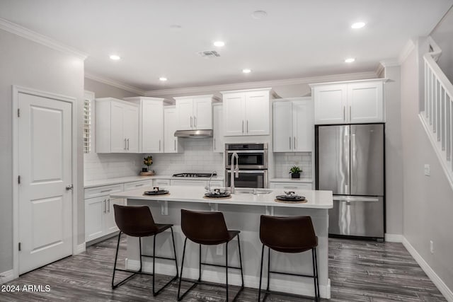 kitchen with white cabinets, dark hardwood / wood-style flooring, stainless steel appliances, and an island with sink