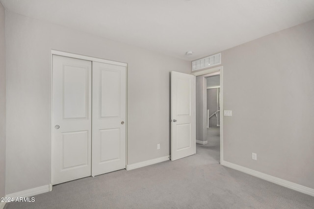 unfurnished bedroom with light carpet and a closet