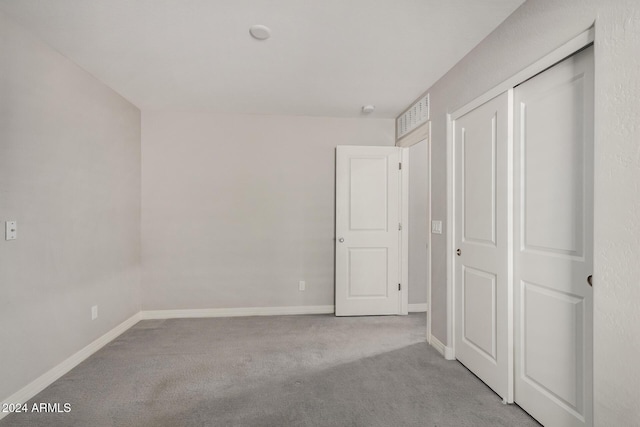 unfurnished bedroom featuring light carpet and a closet