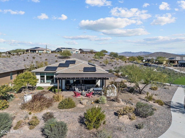 exterior space with a mountain view, solar panels, and a patio