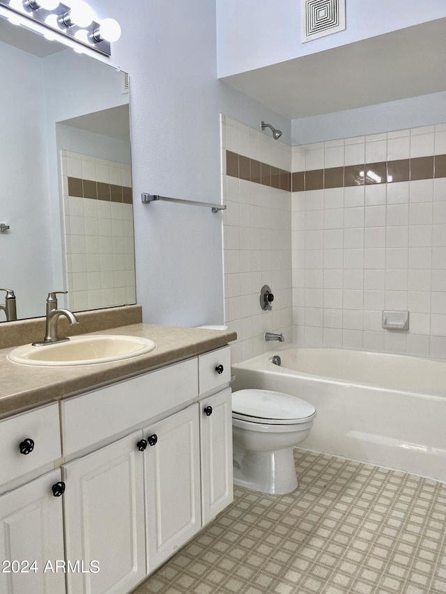 full bathroom with tiled shower / bath, vanity, and toilet