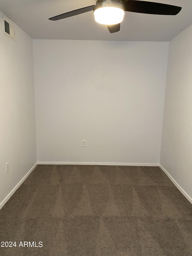 empty room with ceiling fan and dark colored carpet