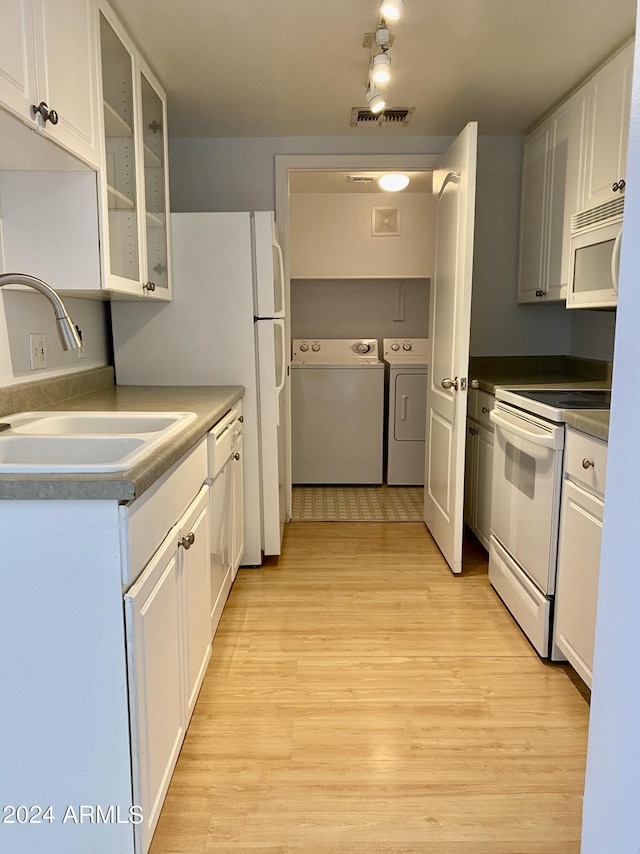 kitchen with sink, white appliances, washer and clothes dryer, white cabinetry, and light hardwood / wood-style floors