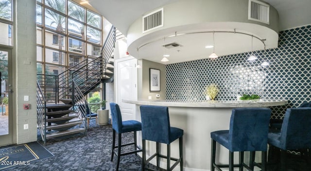 interior space with dark colored carpet, a towering ceiling, and a kitchen bar